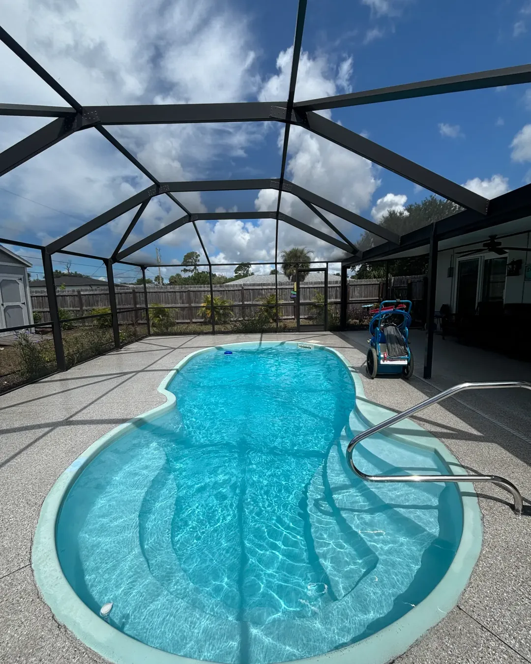 Curved blue swimming pool and clean water under a Florida lanai