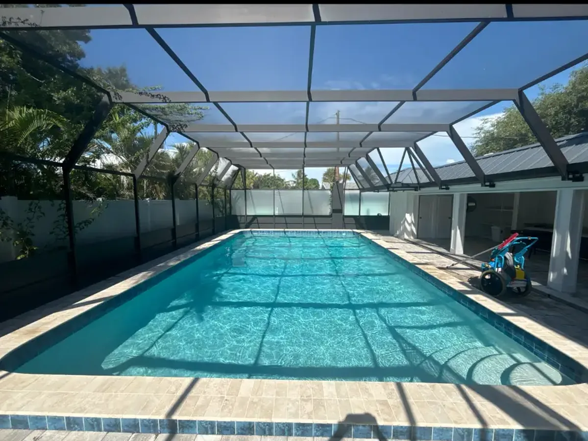 Clean long swimming pool beneath a screened enclosure