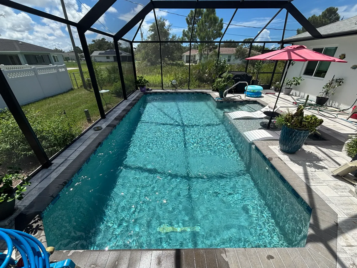 Sunny residential pool with clean blue water inside a screened lanai